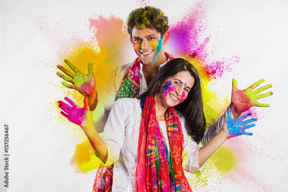 Obraz premium Indian Couple playing colours or people celebrating holi, with holding mobile or white board or pichkari or sweets, isolated over white background
