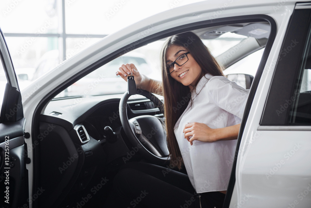 Young happy woman near the car with keys in hand