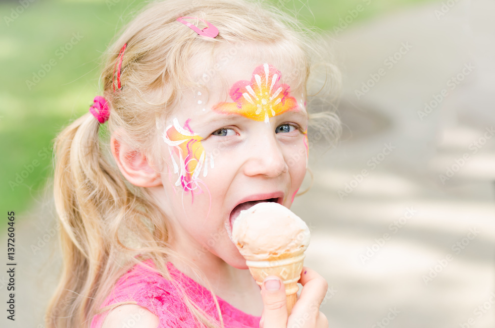 girl with colorful face-painting eating ice cream