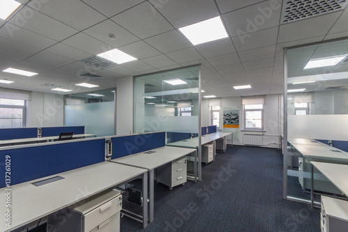 Modern office interior with multiple open-plan work stations at long desks