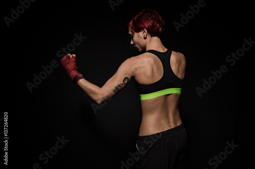 Boxing woman with red boxing wraps on black background