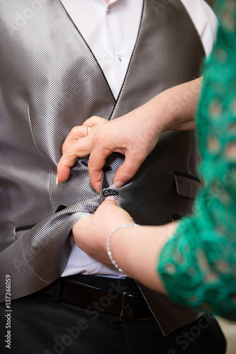 Hands of mother helping his son in his wedding day