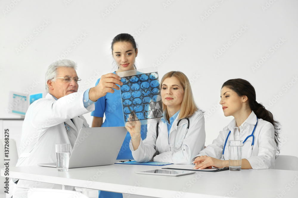 Team of doctors exploring roentgenogram at table Team of doctors exploring roentgenogram at table