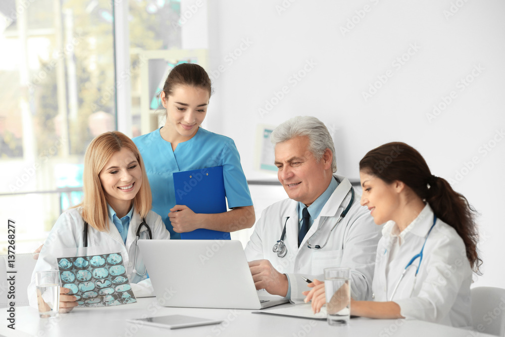 Team of doctors exploring roentgenogram at table Team of doctors exploring roentgenogram at table