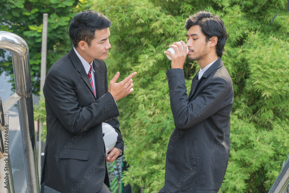 Two Young businessmen talking while standing on a floating staircase. Two Young businessmen talking while standing on a floating staircase.