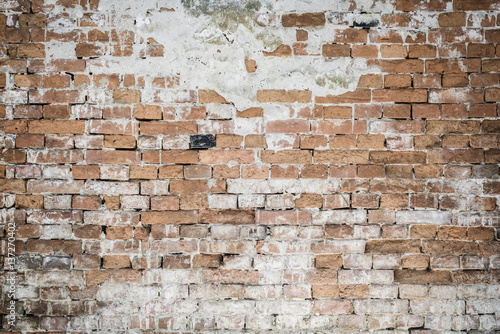 Fragment of old brick wall with multicolored bricks and the plaster showered, background