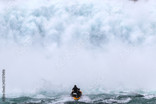 Jet skier riding into a giant wall of water from a dam spillway