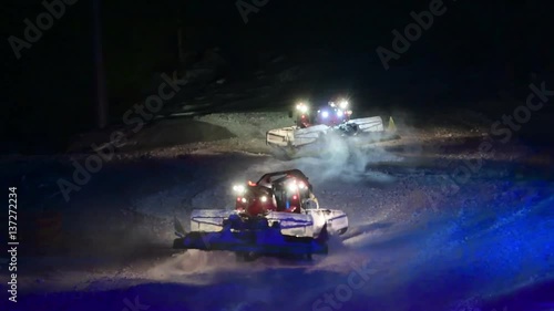 Snow groomers dancing in the snow at night photo