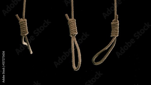 Three rope nooses falling into frame shot in slow motion against black