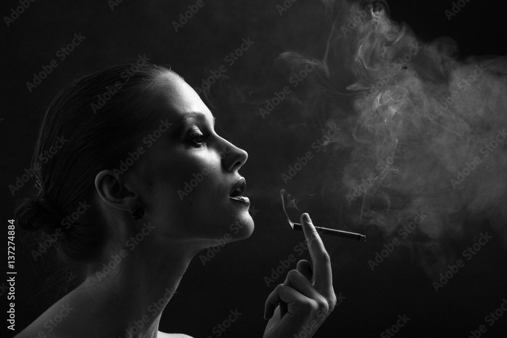 Fototapeta premium luxury woman smoking cigarette on black background, monochrome