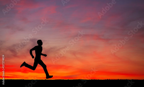 Silhouette of running man on sunset fiery sky background