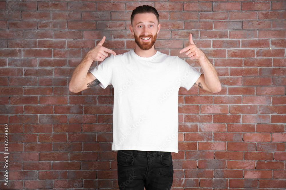 Young handsome man in white T-shirt on brick wall background Young handsome man in white T-shirt on brick wall background