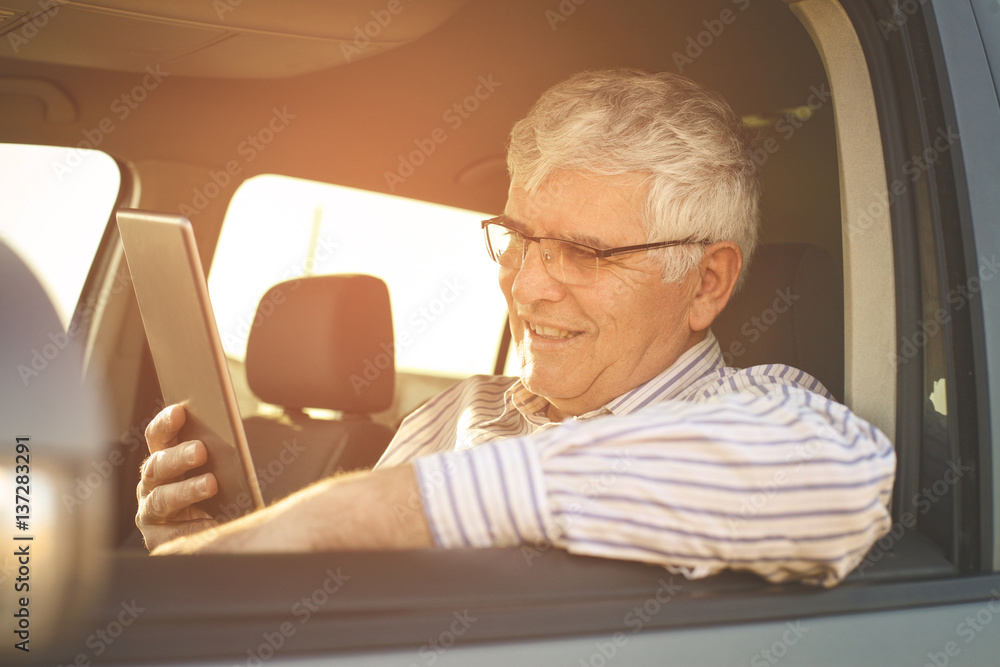 Fototapeta premium Senior man using digital tablet in a car.