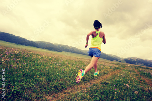 young fitness woman trail runner running on grassland