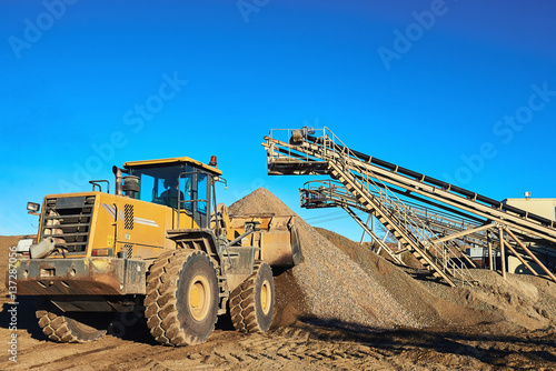 Yellow Bulldozer Working in the background of sky and gravel hills.