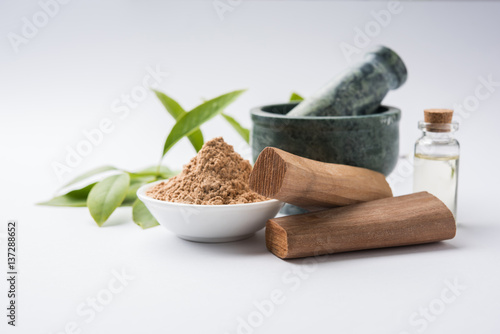 Chandan or sandalwood powder with traditional mortar, sandalwood sticks, perfume or oil and green leaves. selective focus photo