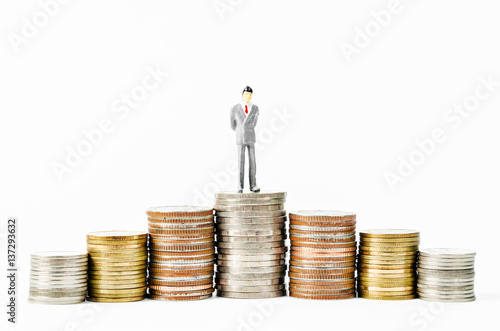 Miniature businessman on many stack of coins money.