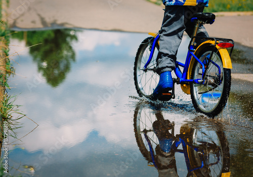 little boy riding bike in water puddle
