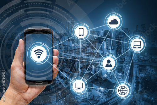 Hand holding smart phone, wireless communication network on city background