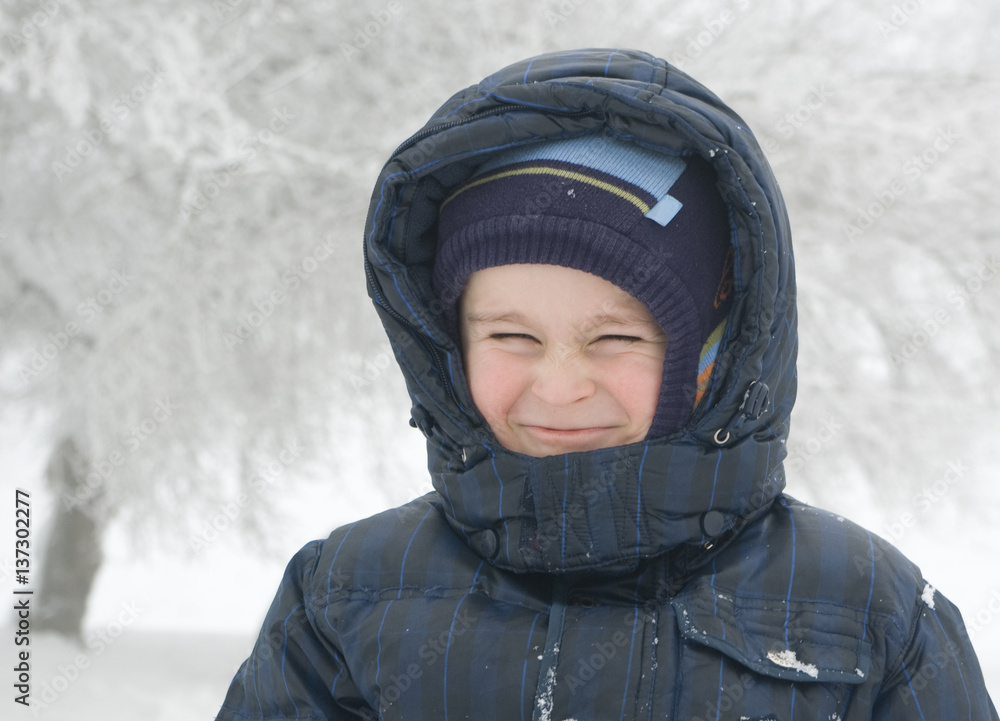 Funny smiling 5.5 y.o. boy on a winter park with trees covered by snow background Funny smiling 5.5 y.o. boy on a winter park with trees covered by snow background