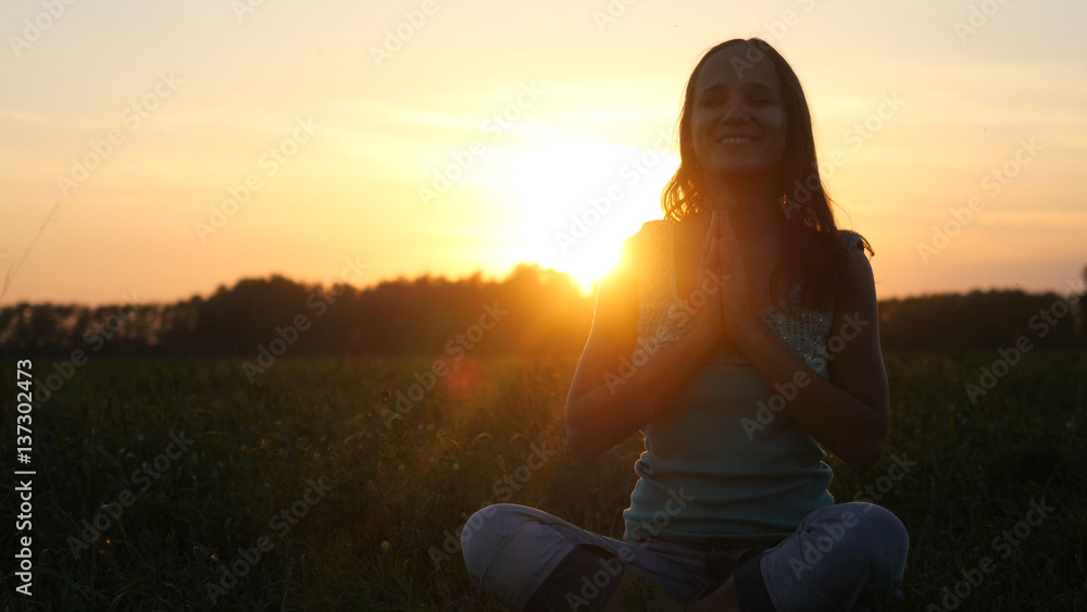 Young pretty woman meditates in nature, in the field during beautiful sunset Young pretty woman meditates in nature, in the field during beautiful sunset