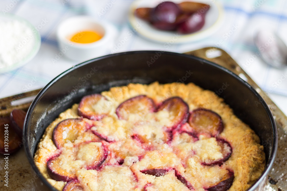 Plum Cake on Light Background with Blue and White Tablecloth and Cooking Ingredients