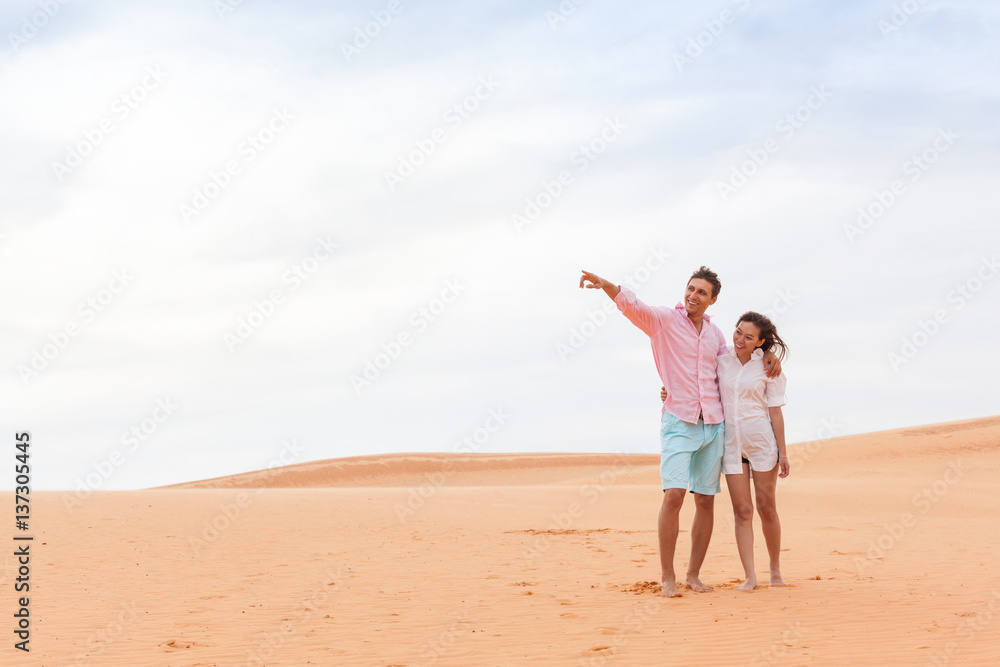 Young Man Woman In Desert Beautiful Couple Asian Girl And Guy Point Finger Embrace Sand Dune Landscape Background