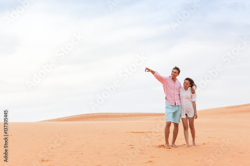 Young Man Woman In Desert Beautiful Couple Asian Girl And Guy Point Finger Embrace Sand Dune Landscape Background