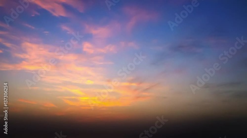 time lapse of clouds crossing the amazing sky over the sea or ocean at sunset. transition from day to night. The clouds cross slowly from left to right colored yellow orange purple blue.