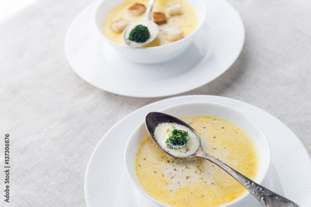 cheese soup with broccoli in a white plate on a white linen tablecloth cheese soup with broccoli in a white plate on a white linen tablecloth