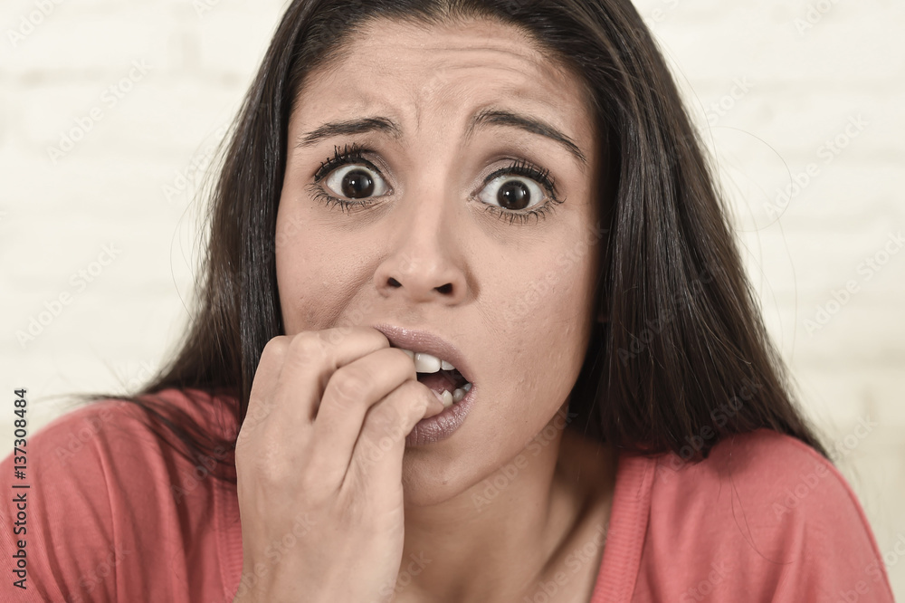 Fototapeta premium latin woman sitting at home sofa couch in living room watching television scary horror movie