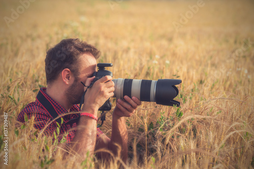Man in wheat field photographing nature.