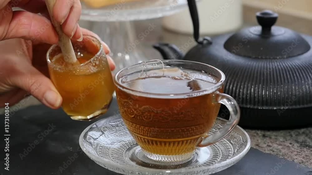 close up of woman adding honey to tea cup close up of woman adding honey to tea cup