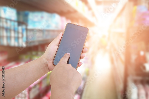 women use mobile phone and blurred image of supermarket. shopping concept.