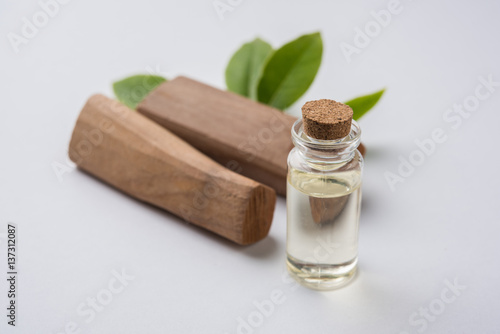 Chandan or sandalwood powder with traditional mortar, sandalwood sticks, perfume or oil and green leaves. selective focus photo