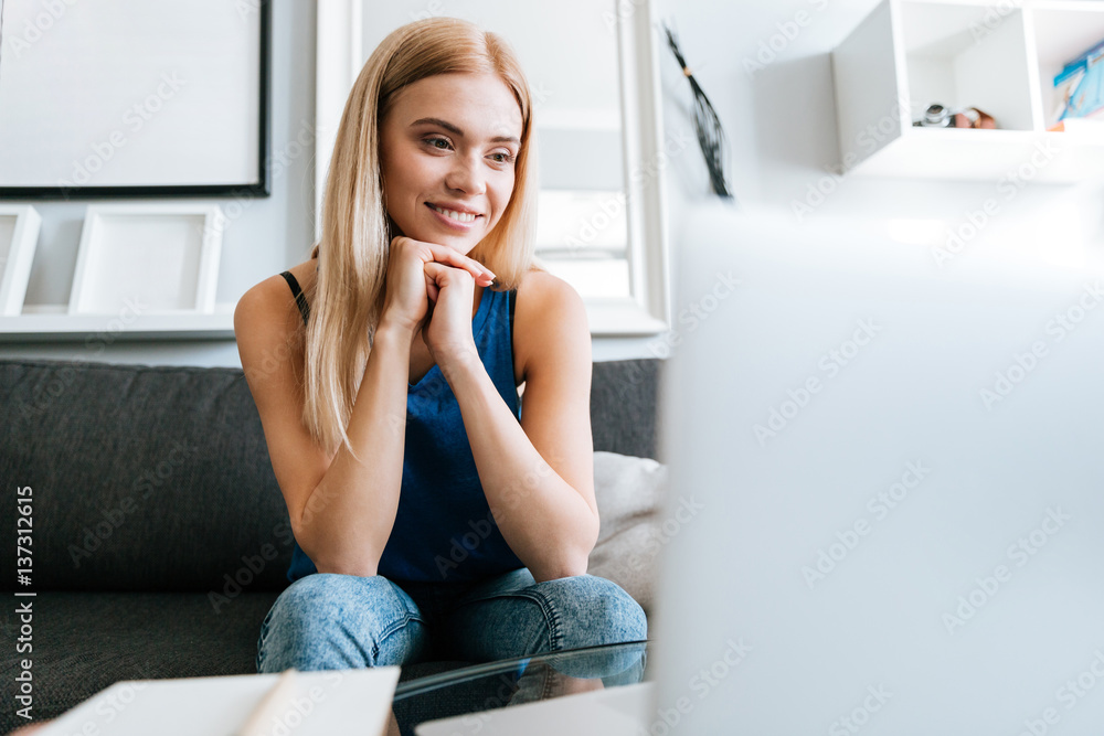Smiling woman sitting on couch at home and thinking Smiling woman sitting on couch at home and thinking