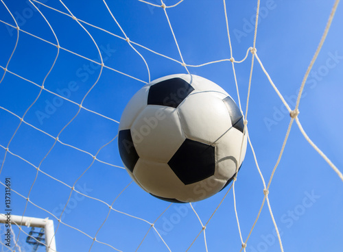 Soccer football in Goal net with sky.