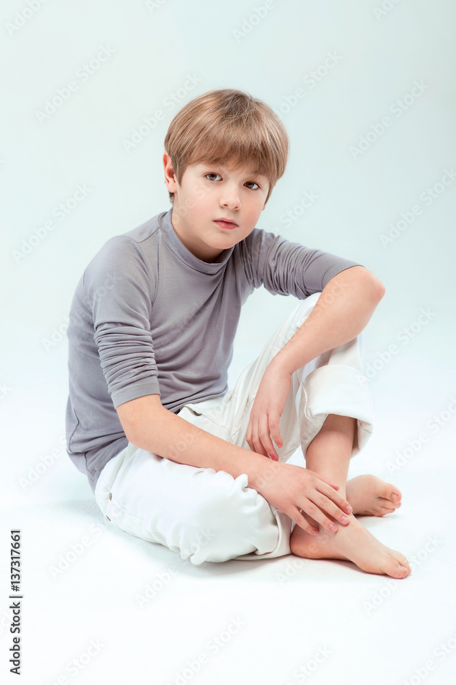 Portrait of cool young stylish boy sitting on light background Portrait of cool young stylish boy sitting on light background