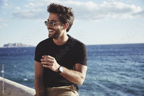 man sitting on wall in front of the ocean photo