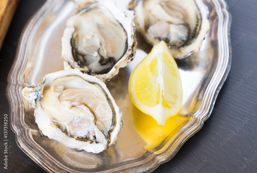 Raw fresh open oysters shells on silver plate close up