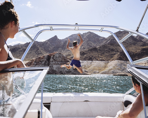 man jumping off a boat in a lake photo