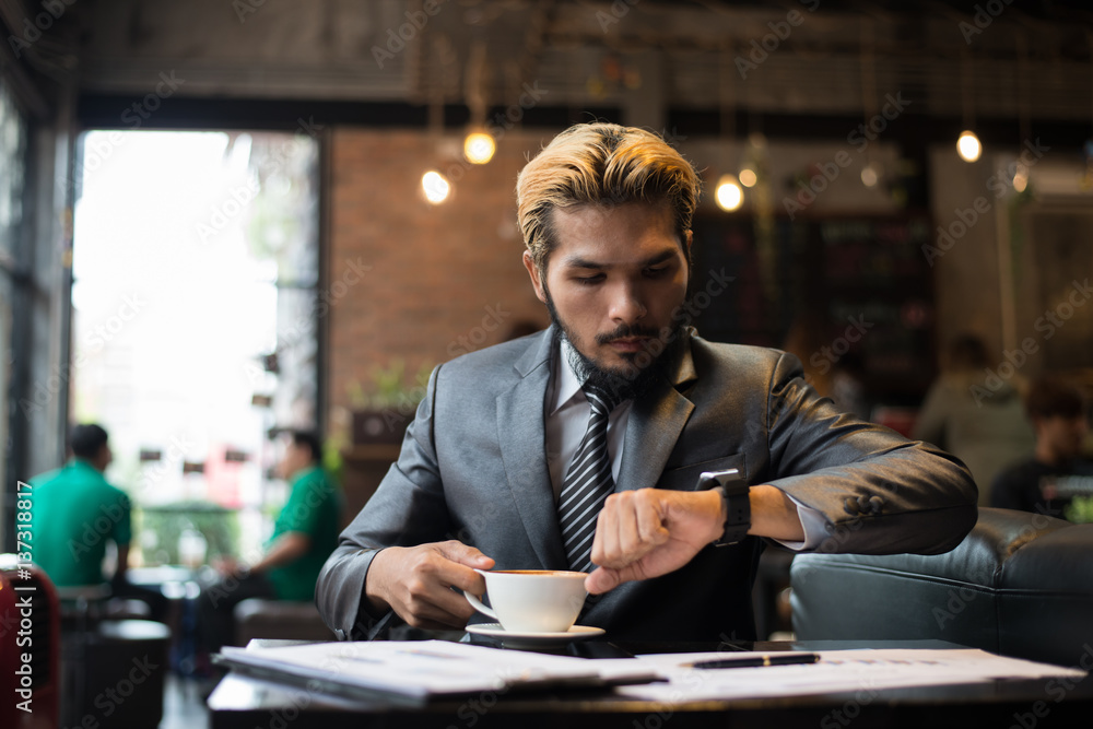 Business man looking at his watch while working at cafe. Business man looking at his watch while working at cafe.