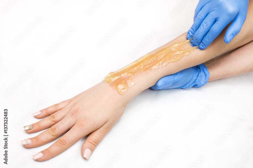 Fototapeta premium Epilation sugar processes woman passes in a beauty salon