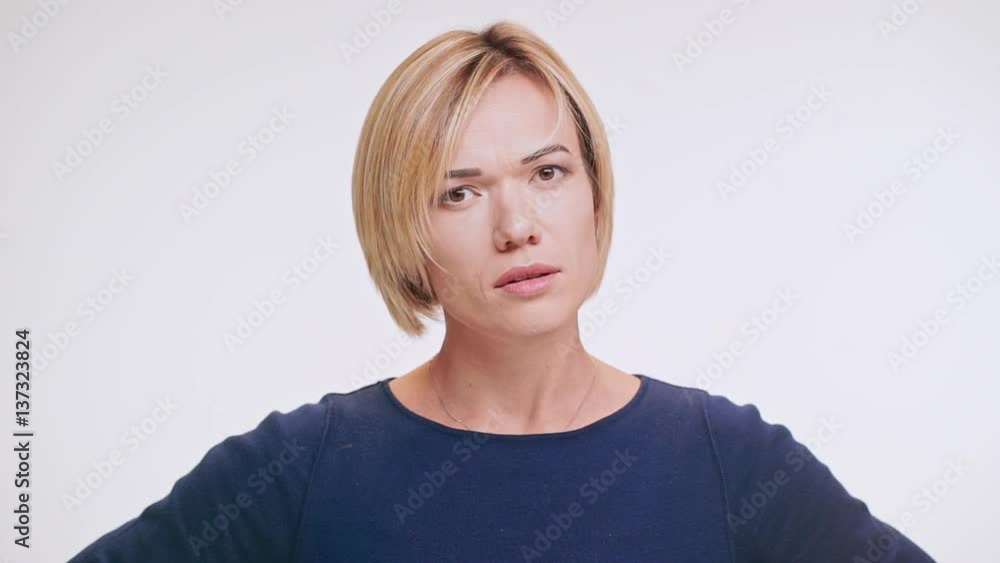 Displeased middle-aged blonde Caucasian female in blue sweatshirt waving no her head on white background in slowmotion Displeased middle-aged blonde Caucasian female in blue sweatshirt waving no her head on white background in slowmotion