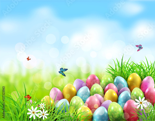 Vector background. Easter eggs in green grass with white flowers, butterflies on blue, blurred , natural background
