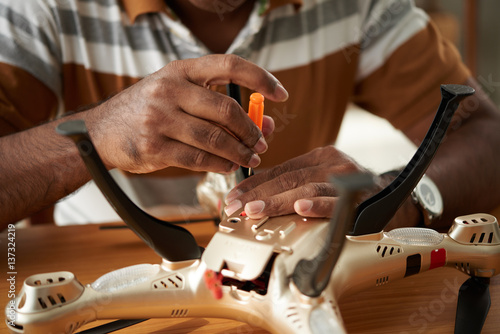 Close-up shot of male hands with screwdriver easing off bolts on quadcopter