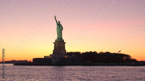 LOW ANGLE: Iconic Statue of Liberty against gorgeous fiery orange sunset sky