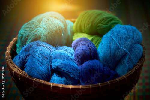 Still life image of colourful cotton in whicker basket. Image made low key.