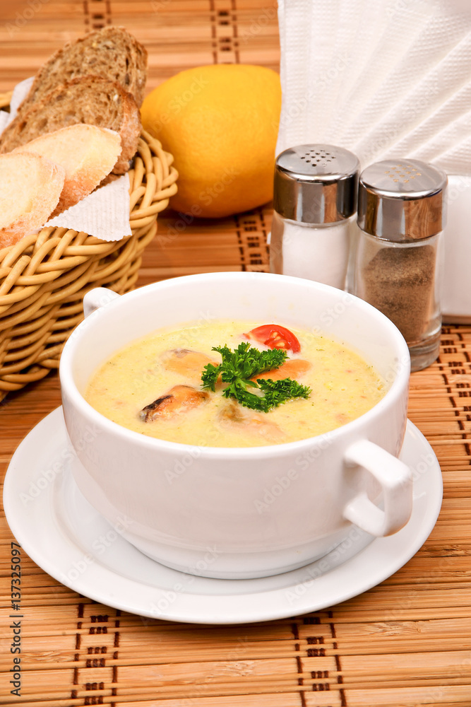 Puree soup of corn with mussels with parsley in a white plate Puree soup of corn with mussels with parsley in a white plate