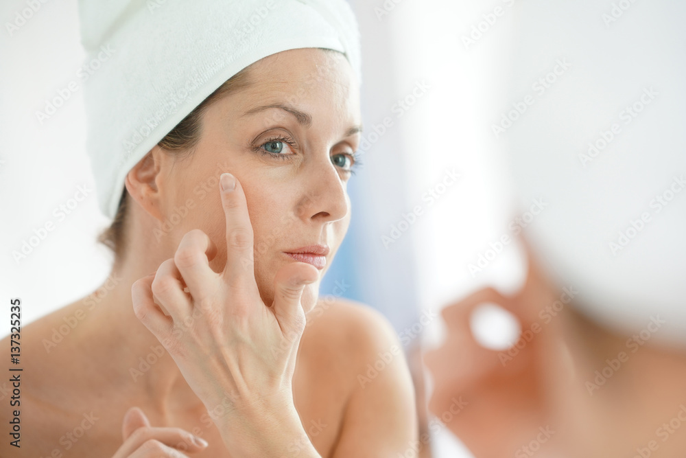 portrait of woman in bathroom applying moisturizing cream portrait of woman in bathroom applying moisturizing cream